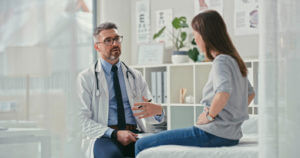 a Digestive Health Specialist sitting with his patient in the clinic and asking questions during a consultation