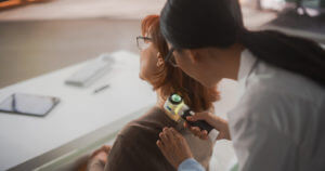 Young Asian Dermatologist is Using a Dermatoscope to Identify Worrying Cancerogenic Tissues on the Skin of a Senior Female During a Health Check Visit to a Clinic