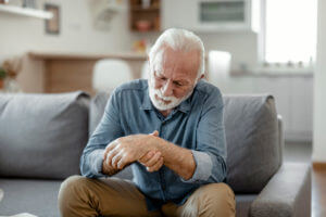 Elderly man holding his wrist in pain from arthritis symptoms.