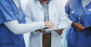 A photo showing a tablet being held by hands, along with a team of doctors at a local medical center.