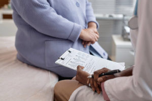 Image of an endocrinologist holding a medical document while with a senior woman patient at the endocrinology clinic.