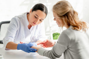 Image of a dermatologist in a white coat, wearing gloves, examining a patient's skin in a clinic.
